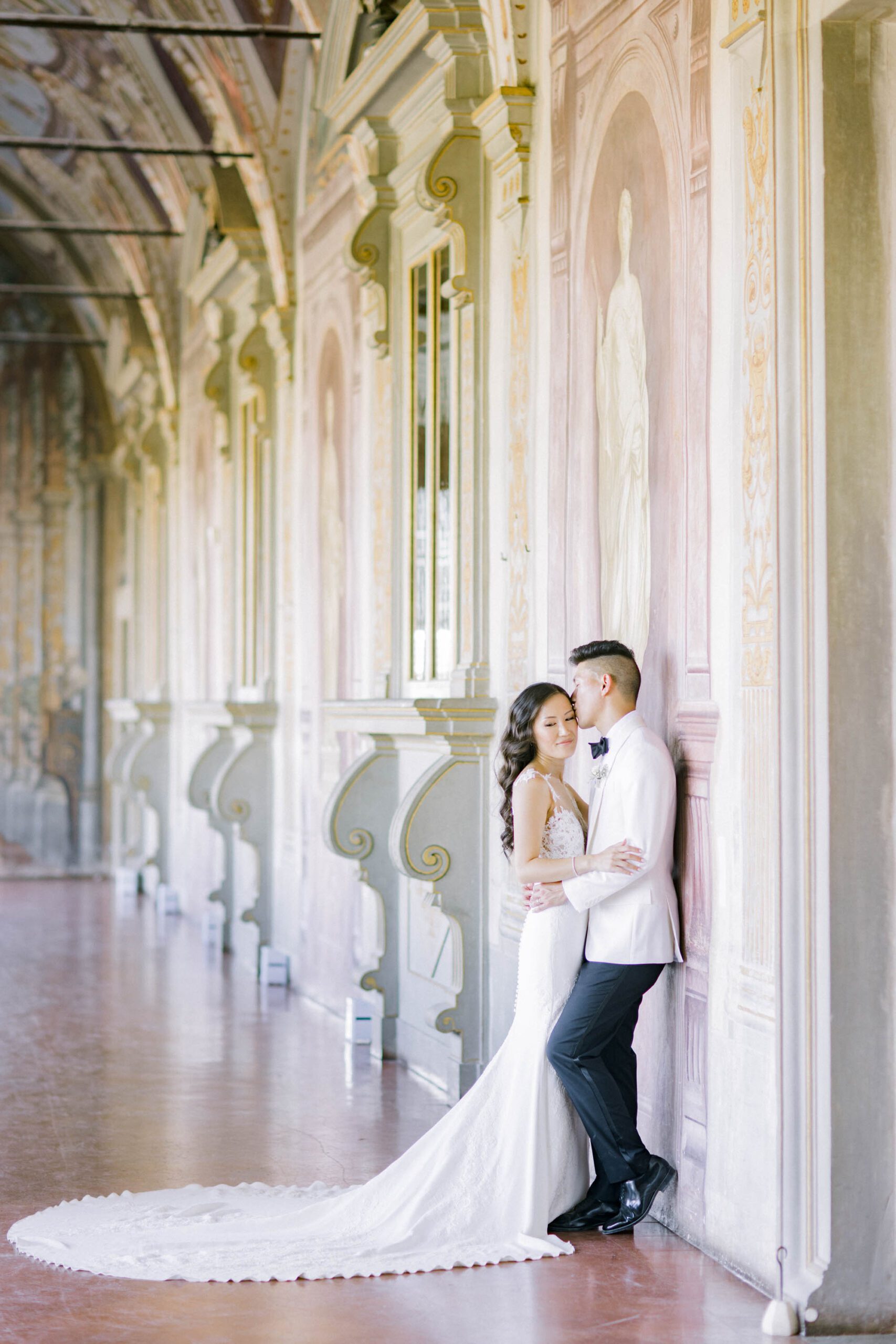 Bride and groom portrait inside Villa Corsini in Tuscany, surrounded by elegant frescoes, chandeliers, and timeless Italian architecture.