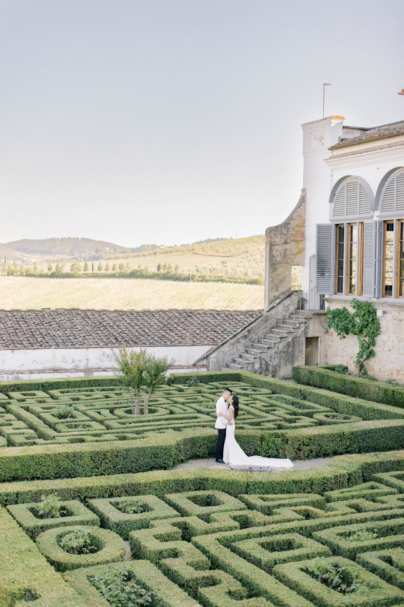 Bride and groom portrait in the historic Garden of Pizzughe at Villa Corsini in Tuscany, surrounded by Italian statues and lush greenery.