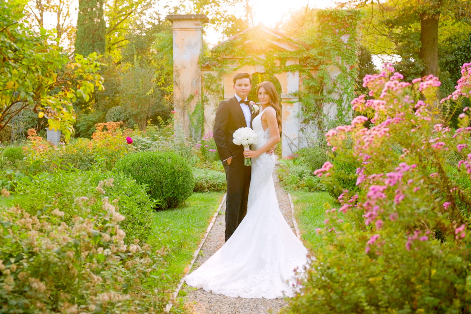 Bride and groom embrace in the gardens of Villa Balbiano at sunset on Lake Como — captured by Koman Studio, fine-art wedding photographers in Italy.