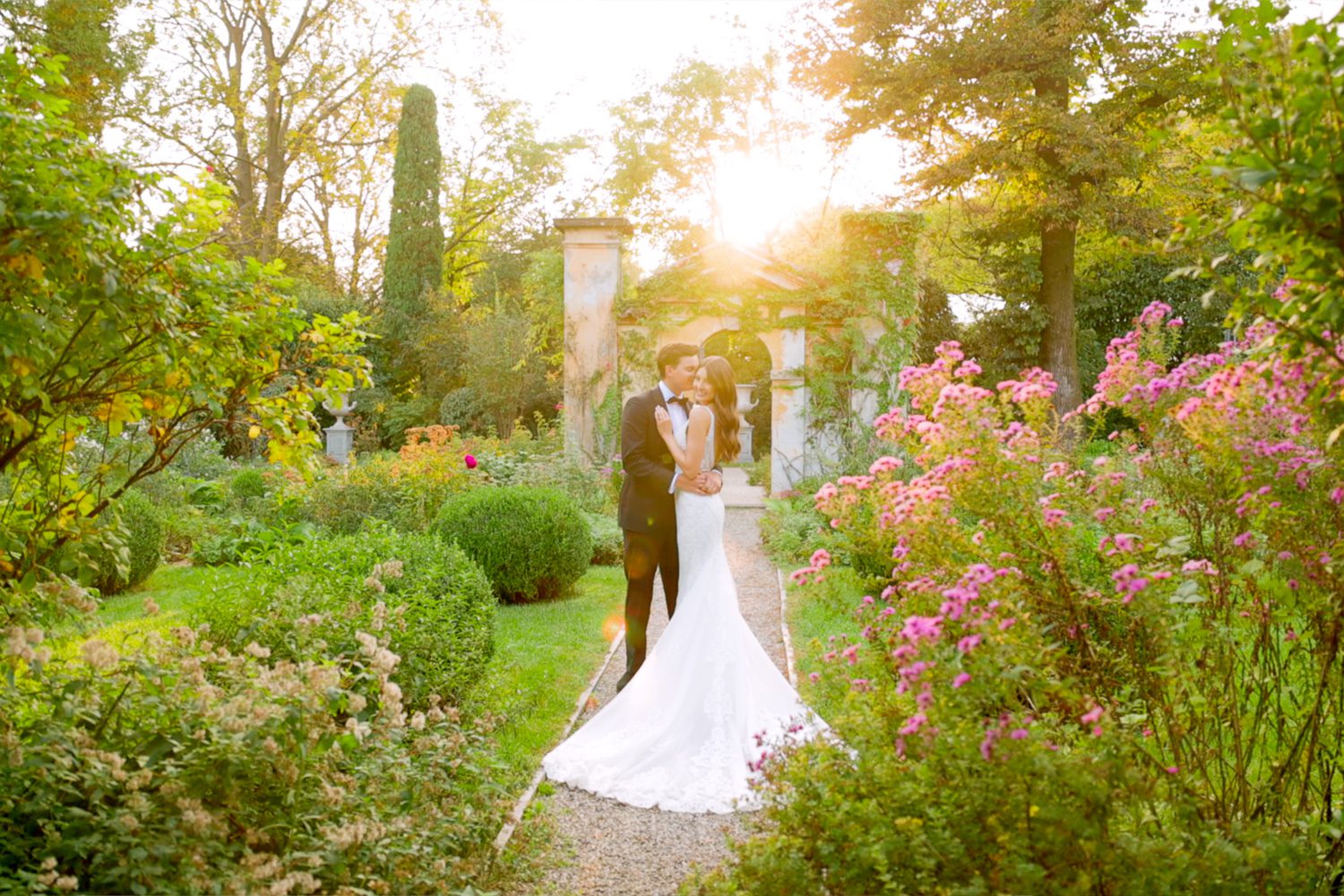 Bride and groom embrace in the gardens of Villa Balbiano at sunset on Lake Como — captured by Koman Studio, fine-art wedding photographers in Italy.