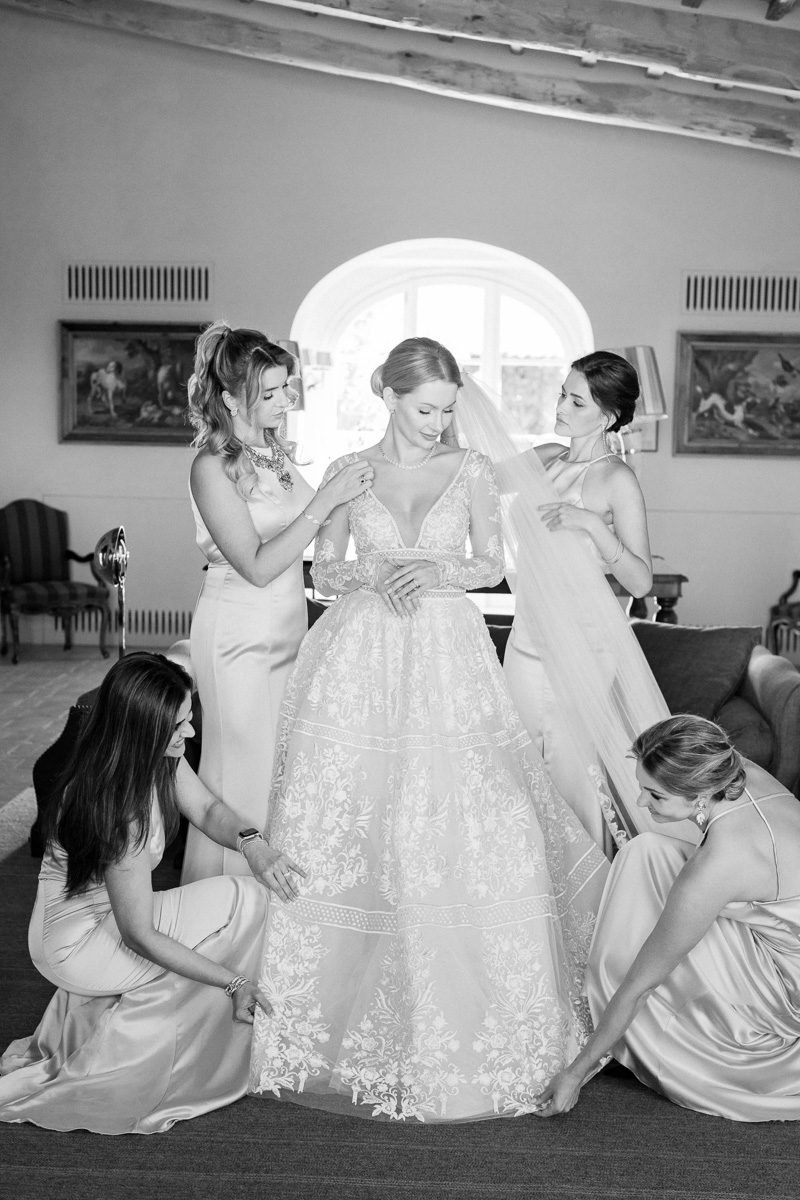 The bride and groom stand together at their ceremony site at Castiglion del Bosco, surrounded by historic Tuscan ruins and rolling Chianti vineyards. This elegant white and green wedding captures the timeless atmosphere of a luxury Tuscany celebration.